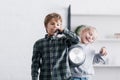 adorable siblings playing with remote controller and frying pan