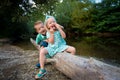 Adorable siblings playing silly by a river, summer outdoors concept