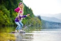 Adorable sisters playing by Hallstatter See lake in Austria on warm summer day. Cute children having fun splashing water and throw