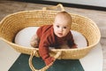 Adorable six month old baby girl in a basket on the floor and looking into the camera. Royalty Free Stock Photo