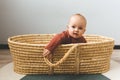 Adorable six month old baby girl in a basket on the floor and looking into the camera. Royalty Free Stock Photo