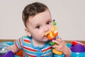 Adorable six month old child chewing a toy. Baby teething.
