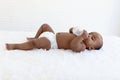 Adorable a sixmonth crawling African American baby lying on fluffy white rug, happy sweet little girl kid holding milk bottle and Royalty Free Stock Photo