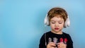 Adorable small three years old boy with cute face expression listening to the music with big white headphones Royalty Free Stock Photo