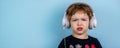 Adorable small three years old boy with cute face expression listening to the music with big white headphones Royalty Free Stock Photo