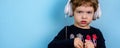 Adorable small three years old boy with cute face expression listening to the music with big white headphones Royalty Free Stock Photo