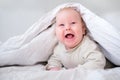 Adorable smiling baby boy under white blanket in bedroom. Newborn child relaxing in bed. Family morning at home. New Royalty Free Stock Photo