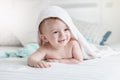 Adorable smiling baby in hooded towel ling on bed after having b Royalty Free Stock Photo