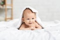 Adorable smiling baby lying on bed under white blanket Royalty Free Stock Photo