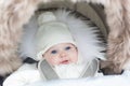 Adorable smiling baby sitting in warm stroller