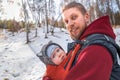 Adorable smiling bearded babywearing father with his baby in sling winter forest walking Royalty Free Stock Photo