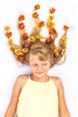 Adorable smiling child with healthy and strong long blond hair in shape of fire with floral arrangement