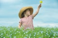 Adorable smiling child in a straw hat with a bouquet of yellow flowers in the middle of a beautiful field of flowers