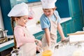 adorable smiling children in chef hats and aprons making dough together Royalty Free Stock Photo