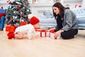 Adorable smiling infant crawling on the parquet to the christmas gifts near his mom which sits on the floor. Royalty Free Stock Photo