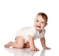 Adorable smiling little baby infant in white cotton bodysuit crawling creeping side to camera looking at us Royalty Free Stock Photo