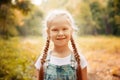 Adorable smiling little blonde girl with braided hair. Cute child having fun on a sunny summer day outdoor.