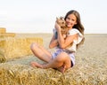 Adorable smiling little girl child sitting on a hay rolls in a wheat field with her small dog pet yorkshire terrier Royalty Free Stock Photo