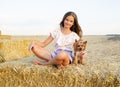Adorable smiling little girl child sitting on a hay rolls in a wheat field with her small dog pet yorkshire terrier Royalty Free Stock Photo