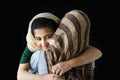 Adorable smiling Pakistani Muslim girl with beautiful eyes wearing hijab, hugging her mother on dark black background, warm love Royalty Free Stock Photo