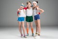 Adorable smiling sporty kids in sportswear standing together on grey