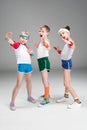 Adorable sporty kids in sportswear standing together and posing on grey
