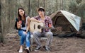 Adorable sweet Asian adult two people or couple sitting at tent in forest for camping, smiling with happiness and freedom, playing Royalty Free Stock Photo