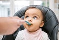 Adorable, sweet and cute baby eating puree for lunch, dinner or snack in her high chair at home. Child development, food Royalty Free Stock Photo