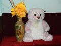 An adorable teddy bear sat on the Sofa with a Flower Vase