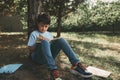 Adorable teenage boy, schoolboy reading a book sitting under tree in the park. School. Education. Childhood Adolescence