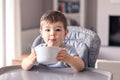 Adorable thankful little baby boy with smeared face just finished his tasty meal and hold white bowl Royalty Free Stock Photo