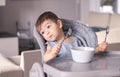 Adorable thoughtful funny little baby boy with smeared face and two forks in hands tired of eating leaning on high feeding chair d