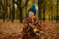 Adorable three year old caucasian boy wearing warm blue jacket and hand knit beanie standing on the lane in a park with a heap of Royalty Free Stock Photo