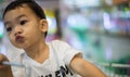 An Adorable toddler Asian boy 1-year-old sitting and play inside the trolley with blurry supermarket background