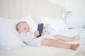 Adorable toddler baby girl sitting on the sofa and playing with smartphone. Royalty Free Stock Photo