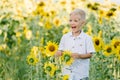 Adorable toddler blond boy in a shirt on sunflower field laughing and having fun outdoors. Life style, summer time, real emotions Royalty Free Stock Photo