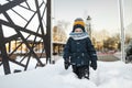 Adorable toddler boy having fun in a city on snowy winter day. Cute child wearing warm clothes playing in a snow Royalty Free Stock Photo