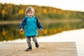 Adorable toddler boy having fun by the Gela lake on sunny fall day. Child exploring nature on autumn day in Vilnius, Lithuania Royalty Free Stock Photo