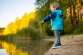 Adorable toddler boy having fun by the Gela lake on sunny fall day. Child exploring nature on autumn day in Vilnius, Lithuania Royalty Free Stock Photo