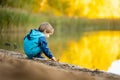 Adorable toddler boy having fun by the Gela lake on sunny fall day. Child exploring nature on autumn day in Vilnius, Lithuania Royalty Free Stock Photo