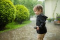 Adorable toddler boy having fun outdoors on rainy summer day. Child under heavy rain Royalty Free Stock Photo