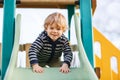 Adorable toddler boy having fun and sliding on outdoor playground Royalty Free Stock Photo