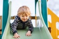 Adorable toddler boy having fun and sliding on outdoor playground Royalty Free Stock Photo