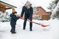 Adorable toddler boy helping his grandfather to shovel snow in a backyard on winter day. Cute child wearing warm clothes playing Royalty Free Stock Photo