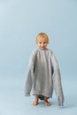 Adorable toddler boy in a huge oversized grey longsleeve over blue