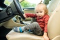 Adorable toddler boy playing in the driver`s seat. Cute little son sitting in fathers car