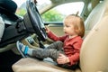 Adorable toddler boy playing in the driver`s seat. Cute little son sitting in fathers car