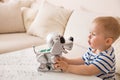 Adorable toddler boy playing with interactive toy. Child with toy robot dog. indoors. Activities for small children. Communication