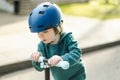 Adorable toddler boy riding his scooter in a city on sunny summer evening. Young child riding a roller