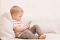 Adorable toddler boy sitting on the sofa in the living room and playing with smartphone. Child learning how to use smartphone. Boy Royalty Free Stock Photo